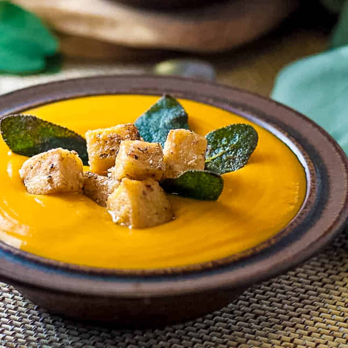 Polenta croutons and sage leaves on a bowl of chipotle sweet potato soup.