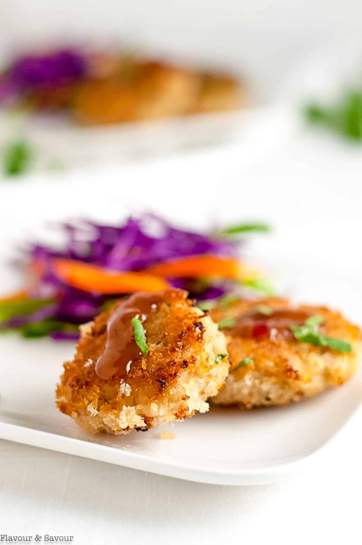 Thai crab cakes on a plate with dipping sauce.