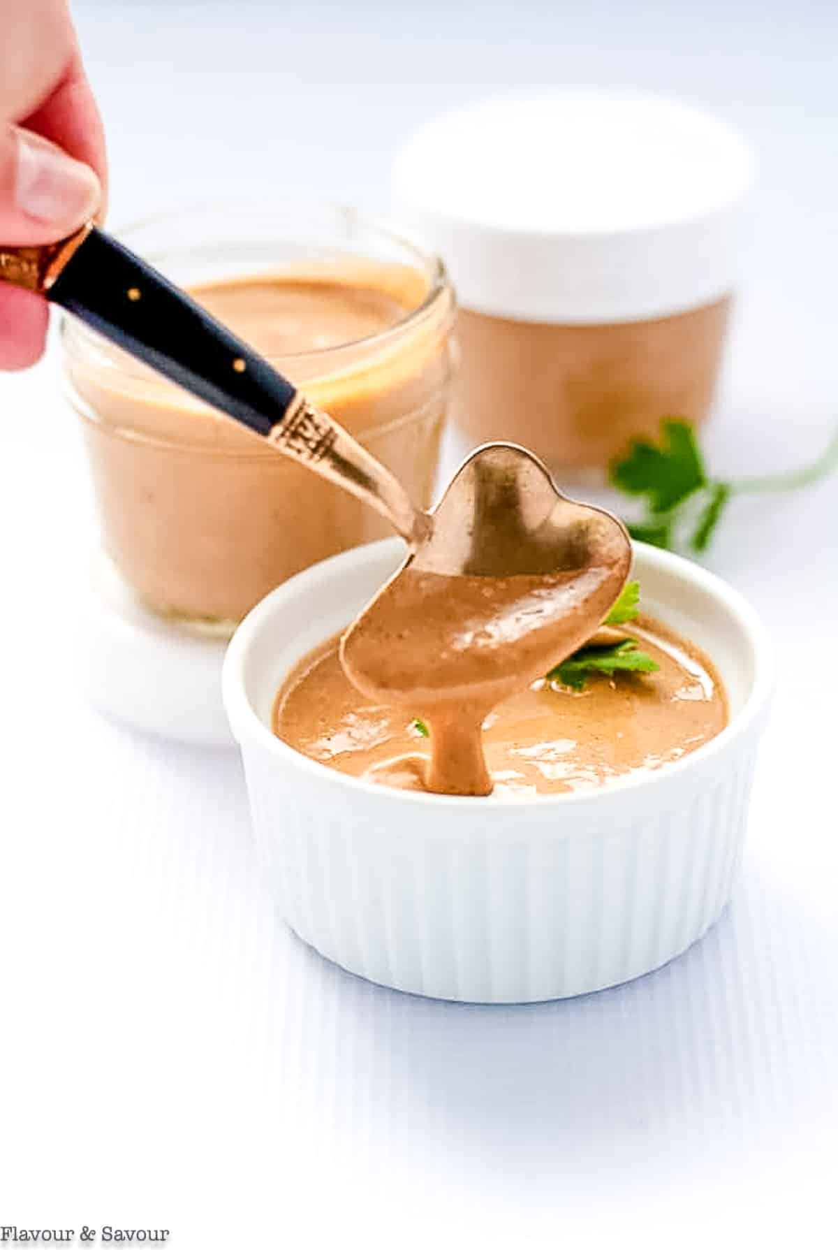 a spoonful of homemade peanut sauce with small jars of sauce in the background.