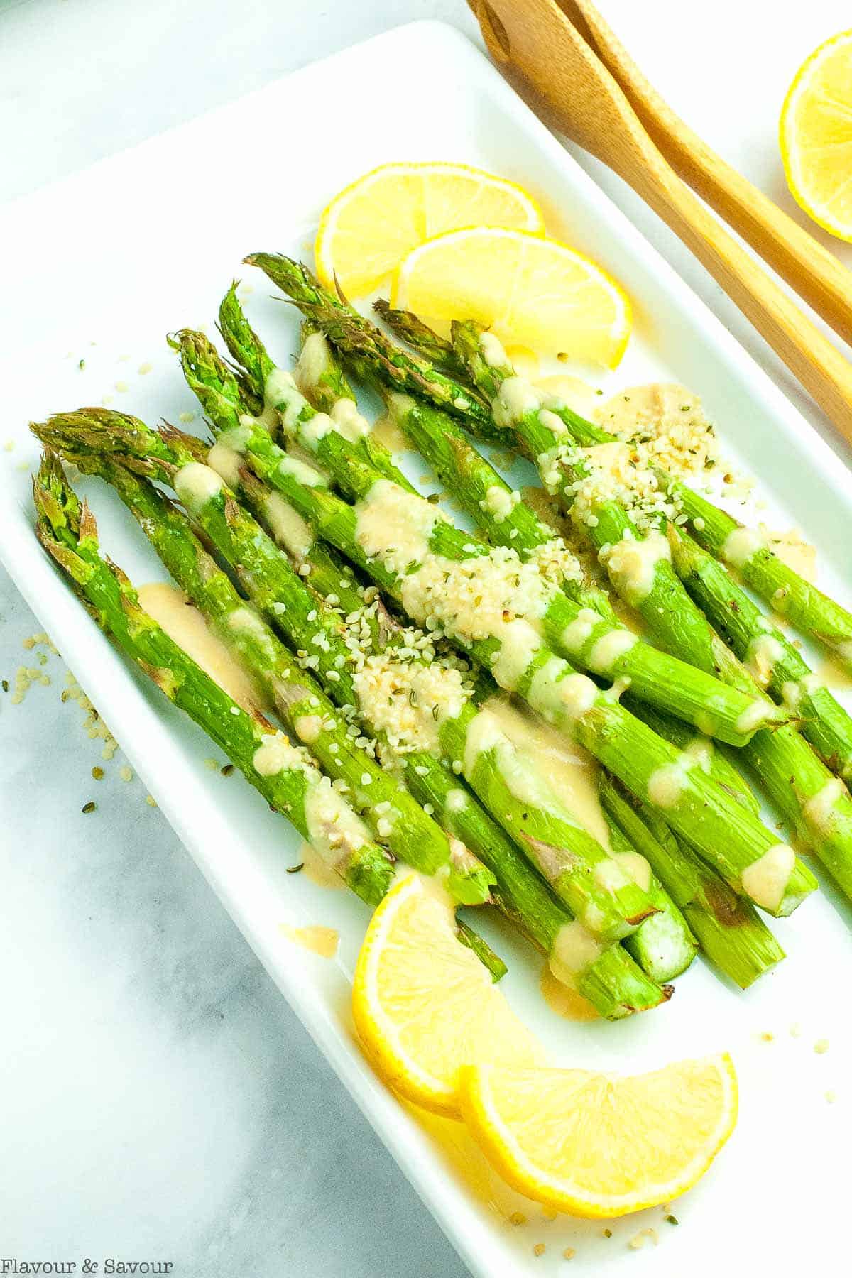 a platter of asparagus spears with lemon tahini sauce and hemp hearts