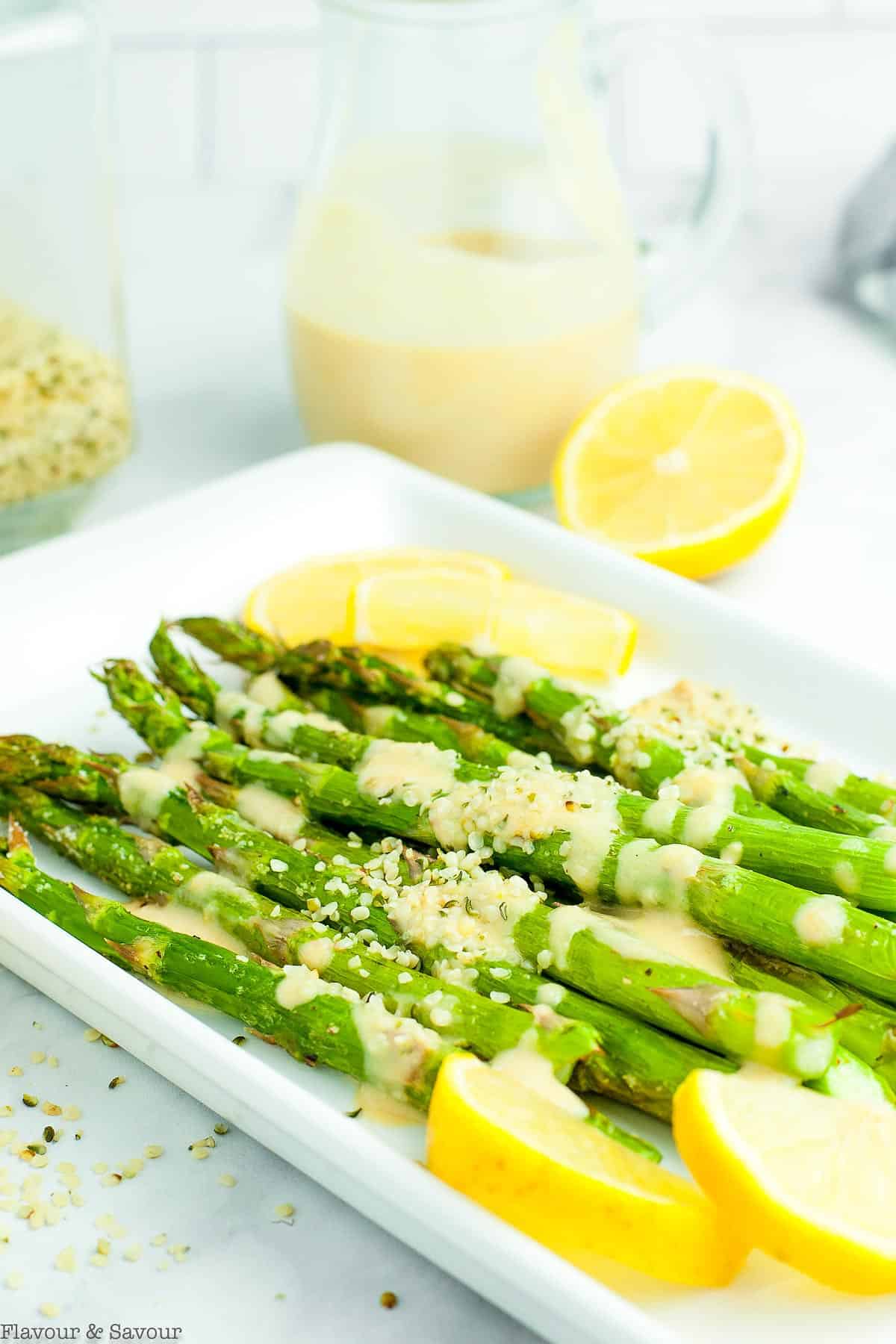 a tray of asparagus spears with lemon tahini sauce.