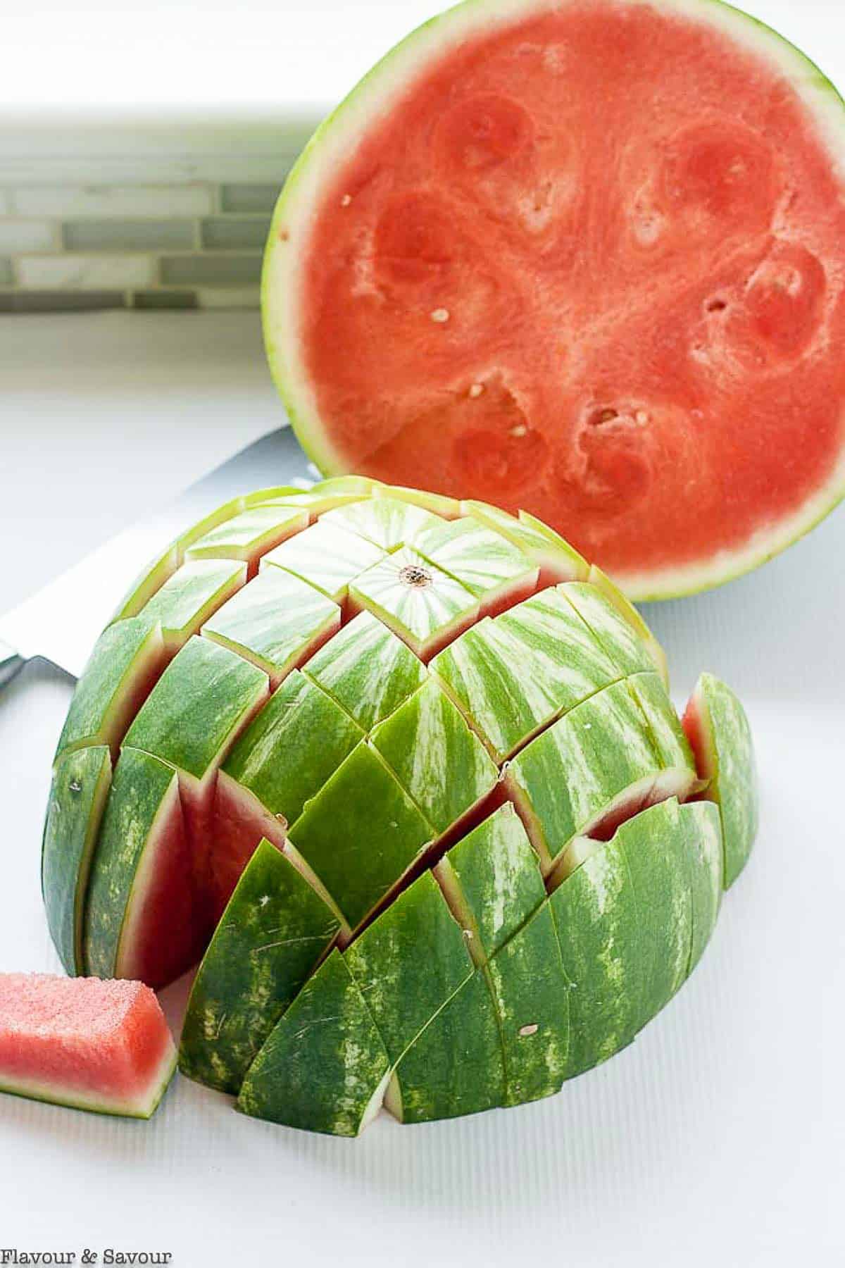 A watermelon split in half with one half cut into spears.