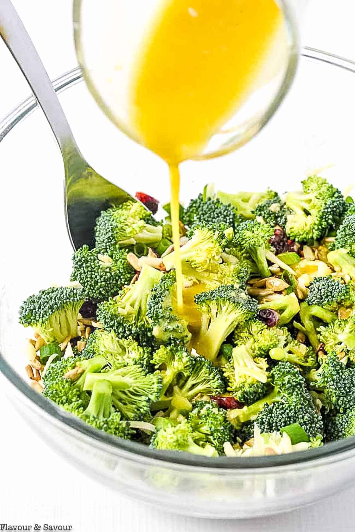 pouring honey-dijon dressing on broccoli salad