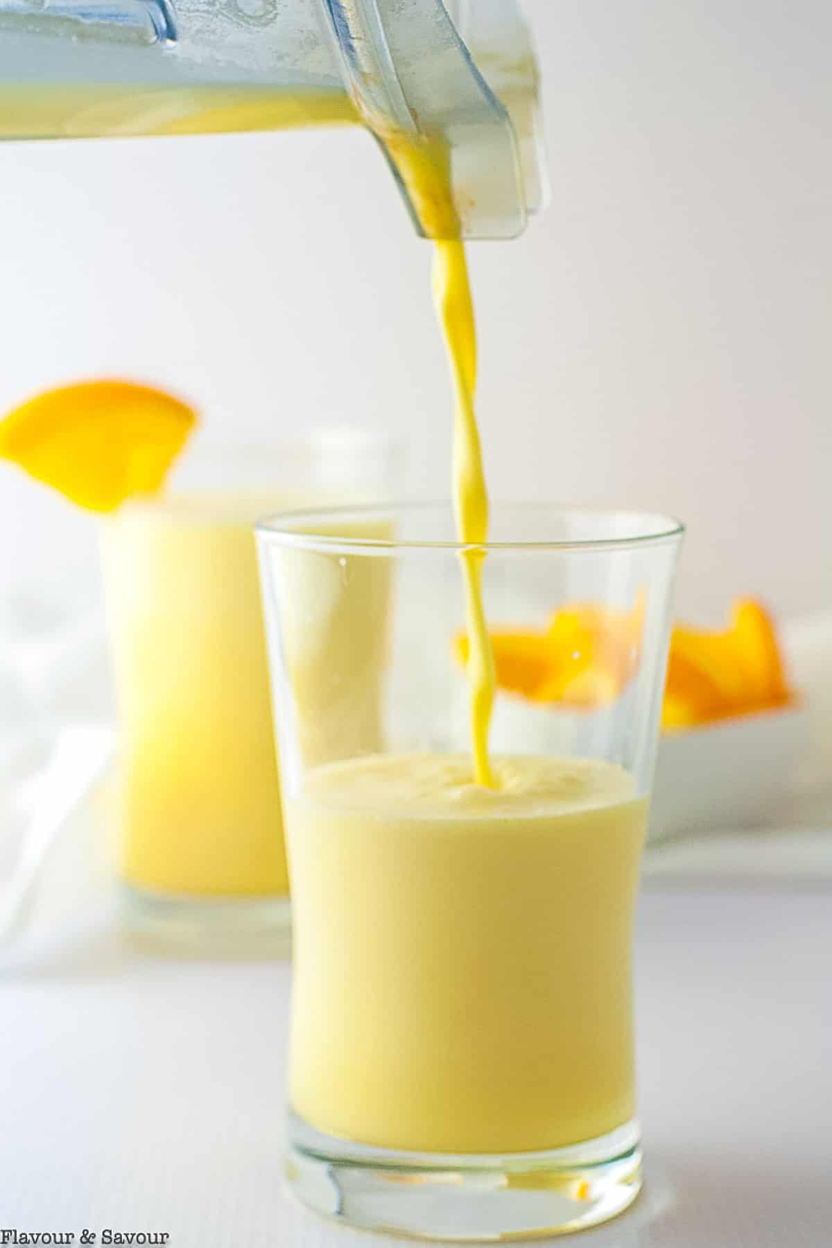 pouring orange collagen creamsicle shake from a blender into a glass