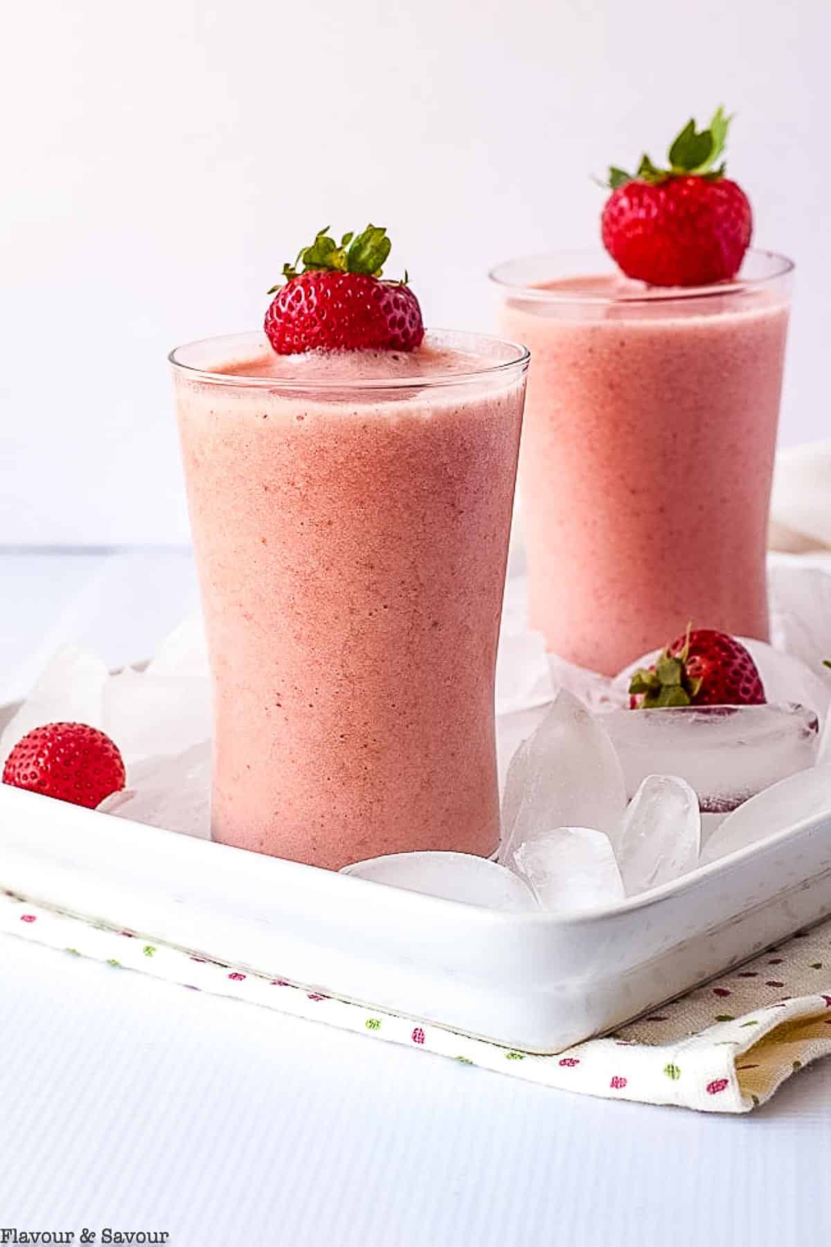 Two glasses of strawberry watermelon collagen smoothie with fresh strawberries.
