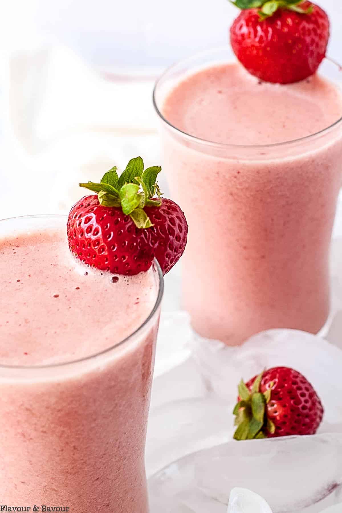 Strawberry watermelon collagen smoothie in two glasses garnished with strawberries.