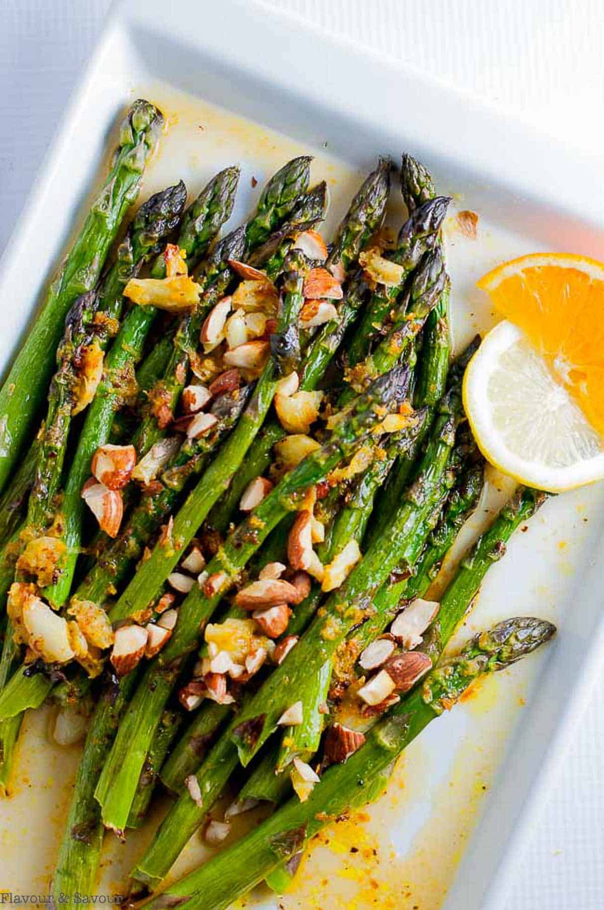 a platter of charred asparagus with warm citrus sauce and chopped almonds