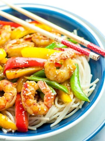 a bowl of shrimp stir fry with chopsticks