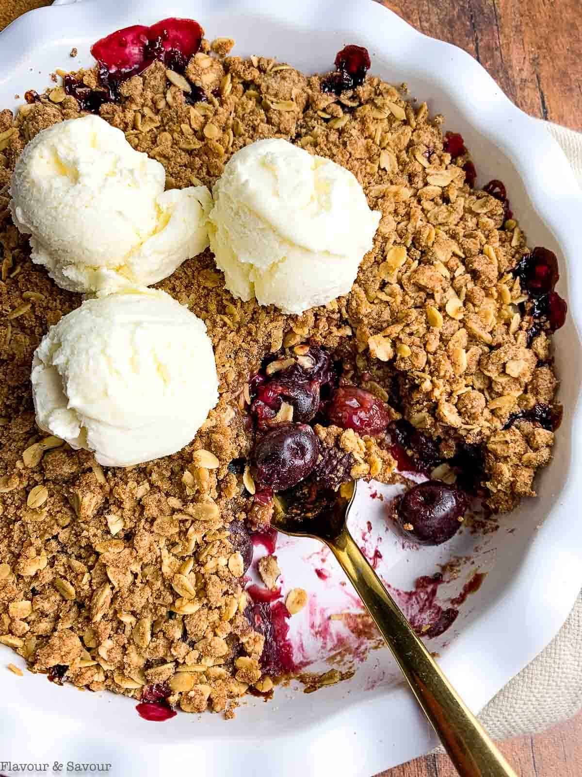 Overhead view of a baking dish with cherry crisp and ice cream.