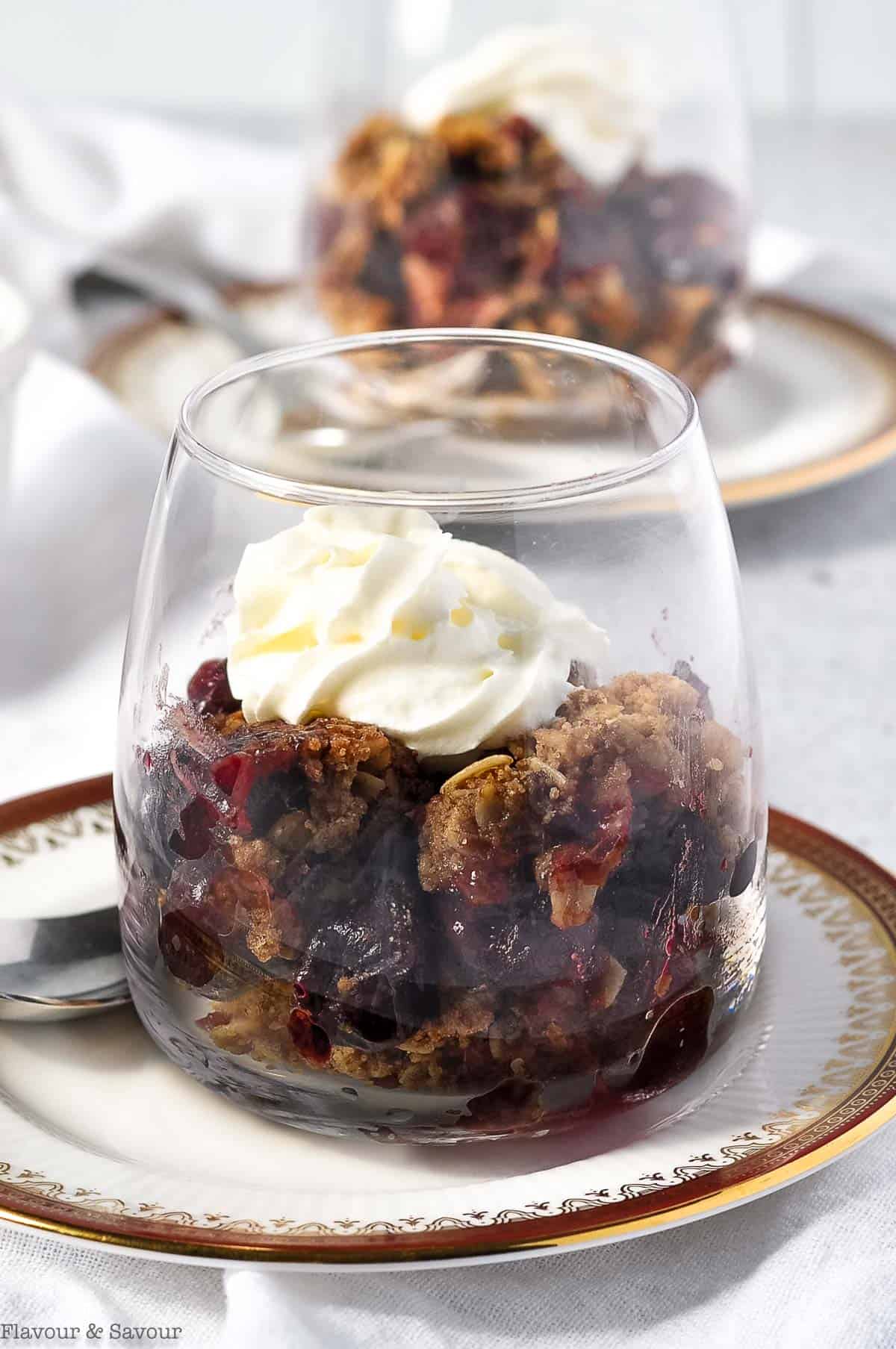 Close up view of a dessert glass with cherry crisp.