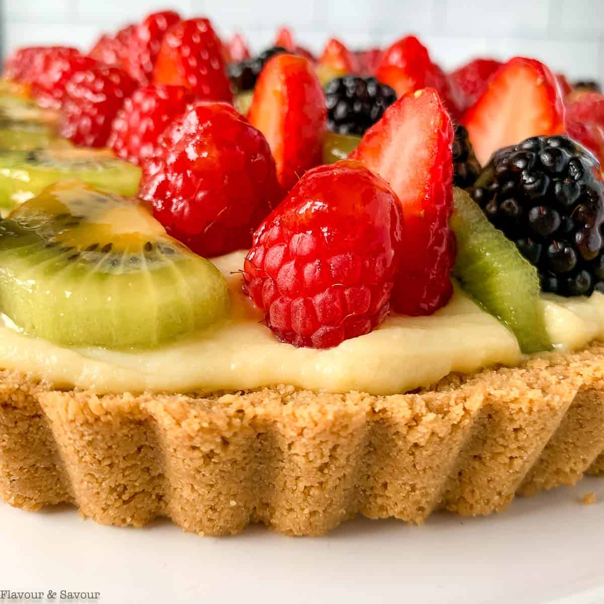 Close up view of a gluten-free fruit tart with fresh berries and fruit .