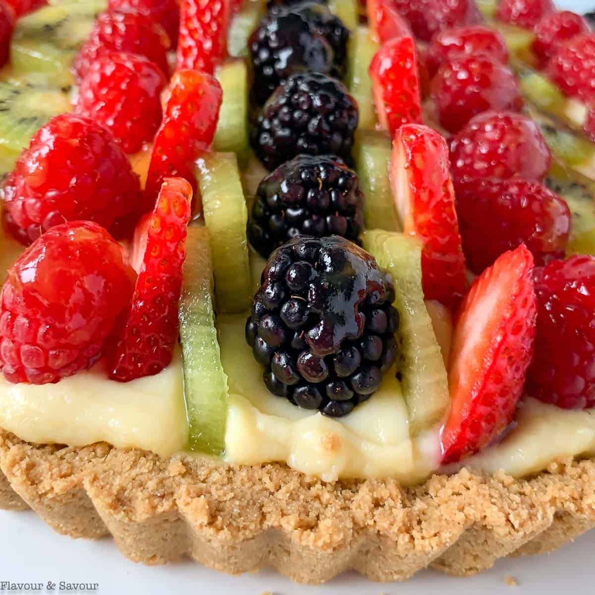 Close up view of berries and kiwi fruit on a gluten-free fruit tart.