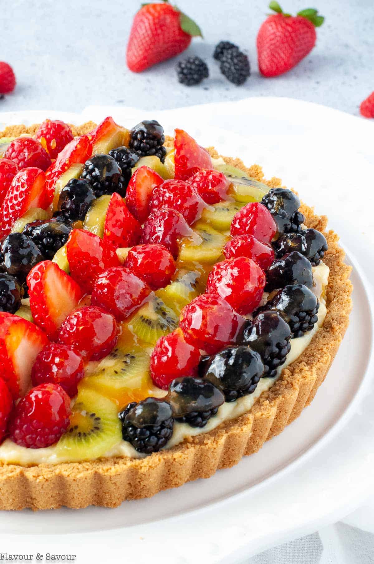 A fruit tart with vanilla pastry cream and rows of fresh berries and fruit.