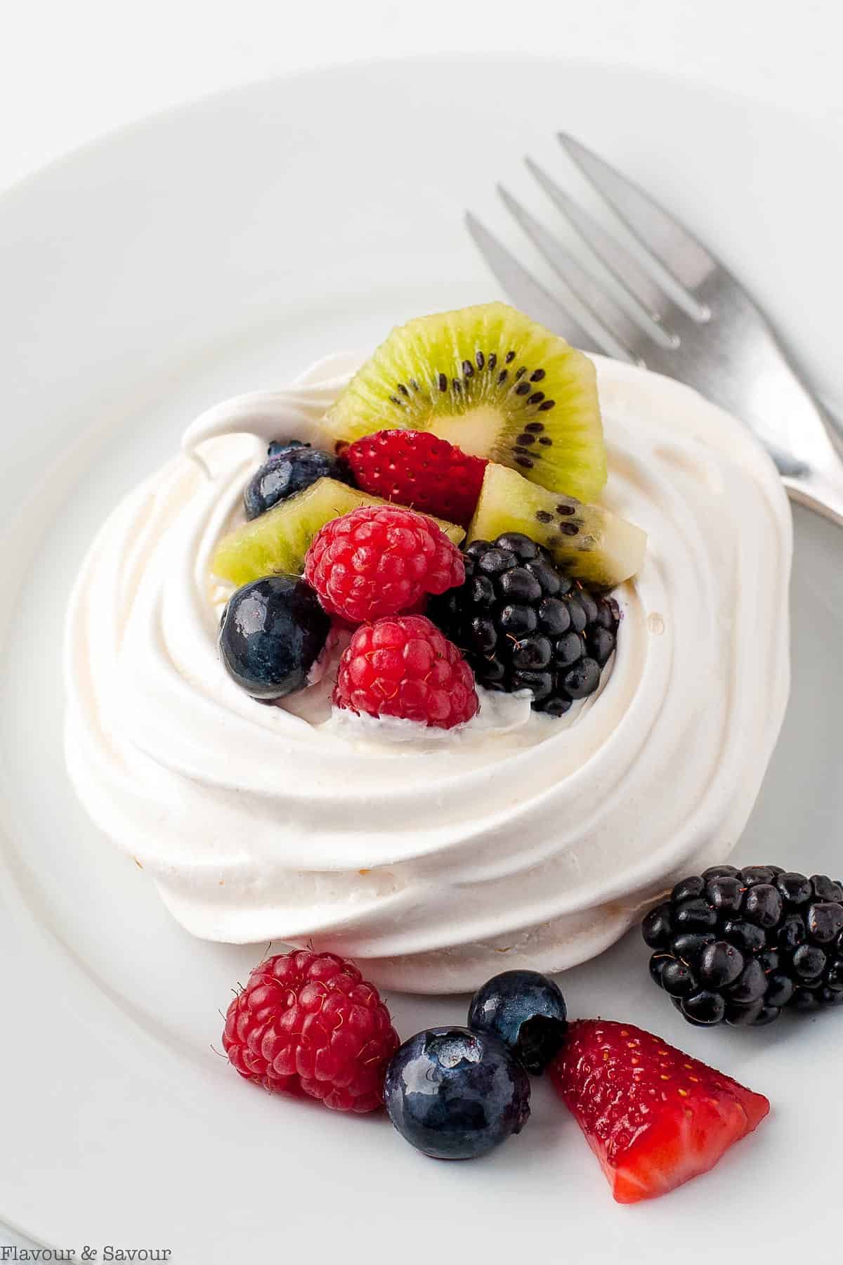 individual pavlova dessert on a white plate with fresh berries