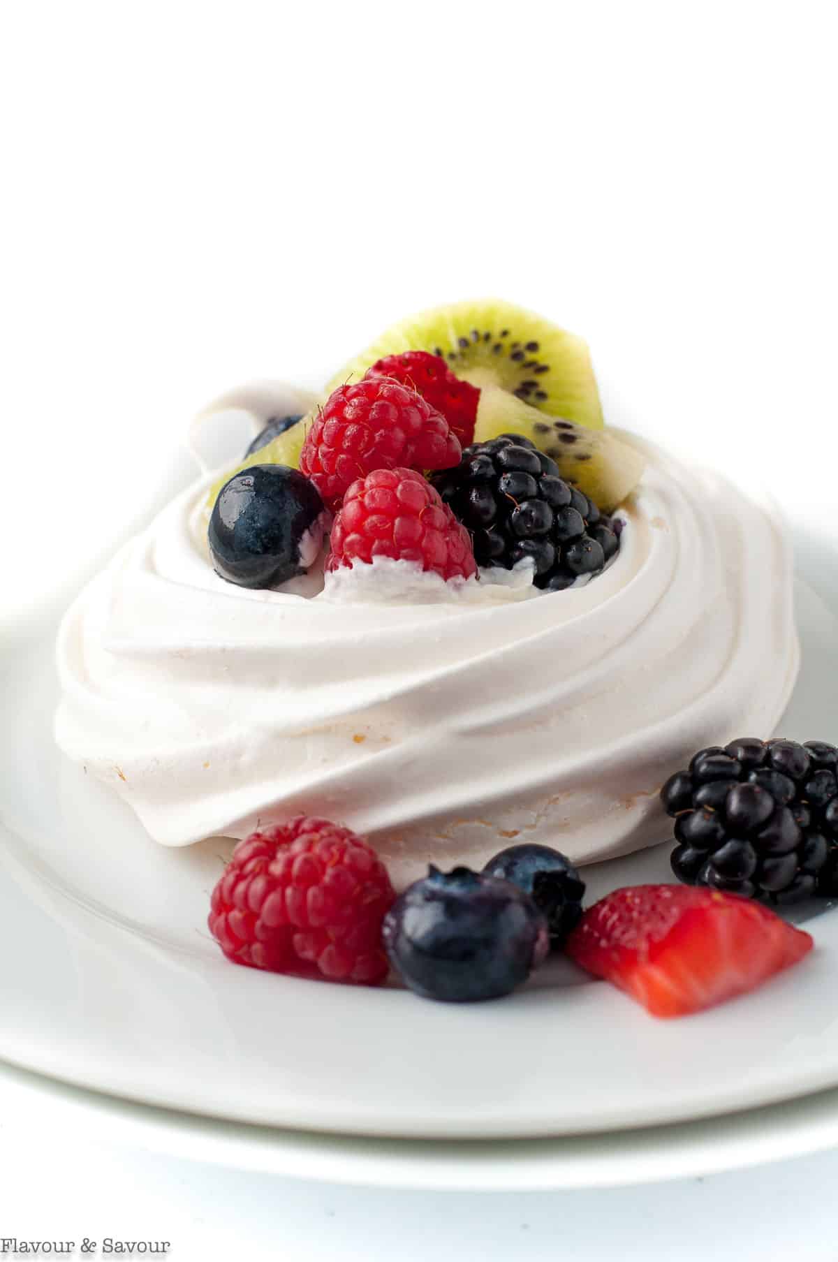 Close up view of pavlova with blueberries, blackberries, strawberries and kiwi.