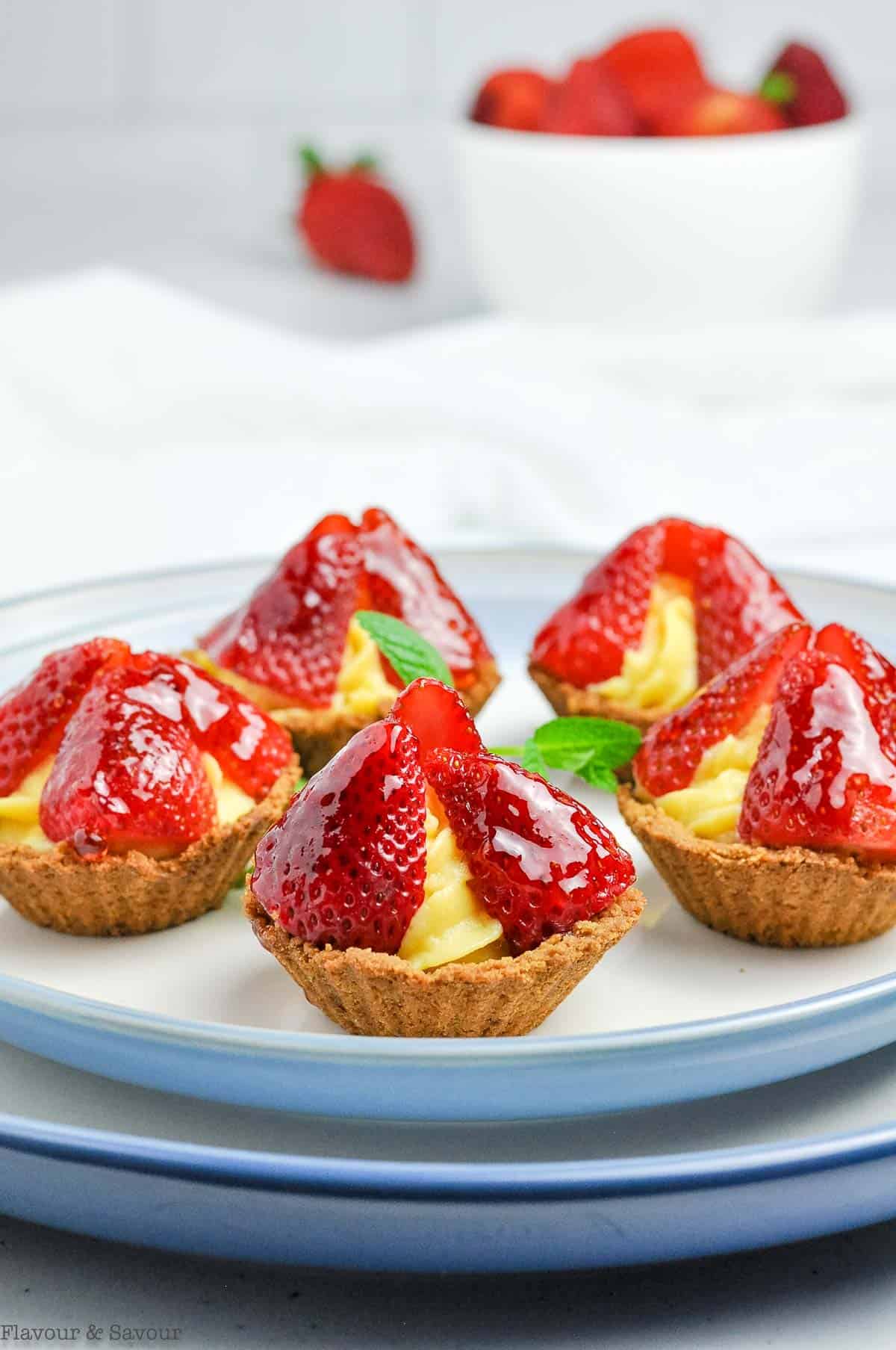 small strawberry tarts with vanilla pastry cream and a graham cracker crust.