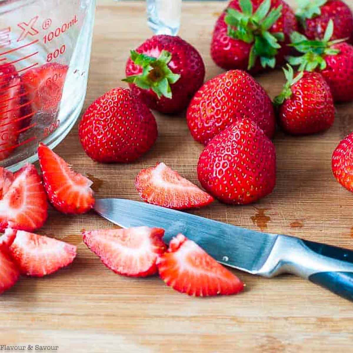 Sliced strawberries on a cutting board.