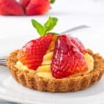 Strawberry tart with pastry cream, fresh sliced strawberries and a mint leaf.