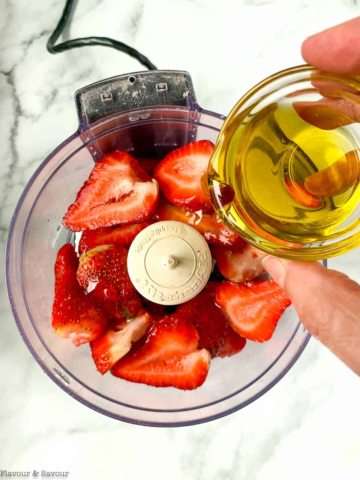 Adding oil to strawberry vinaigrette ingredients.