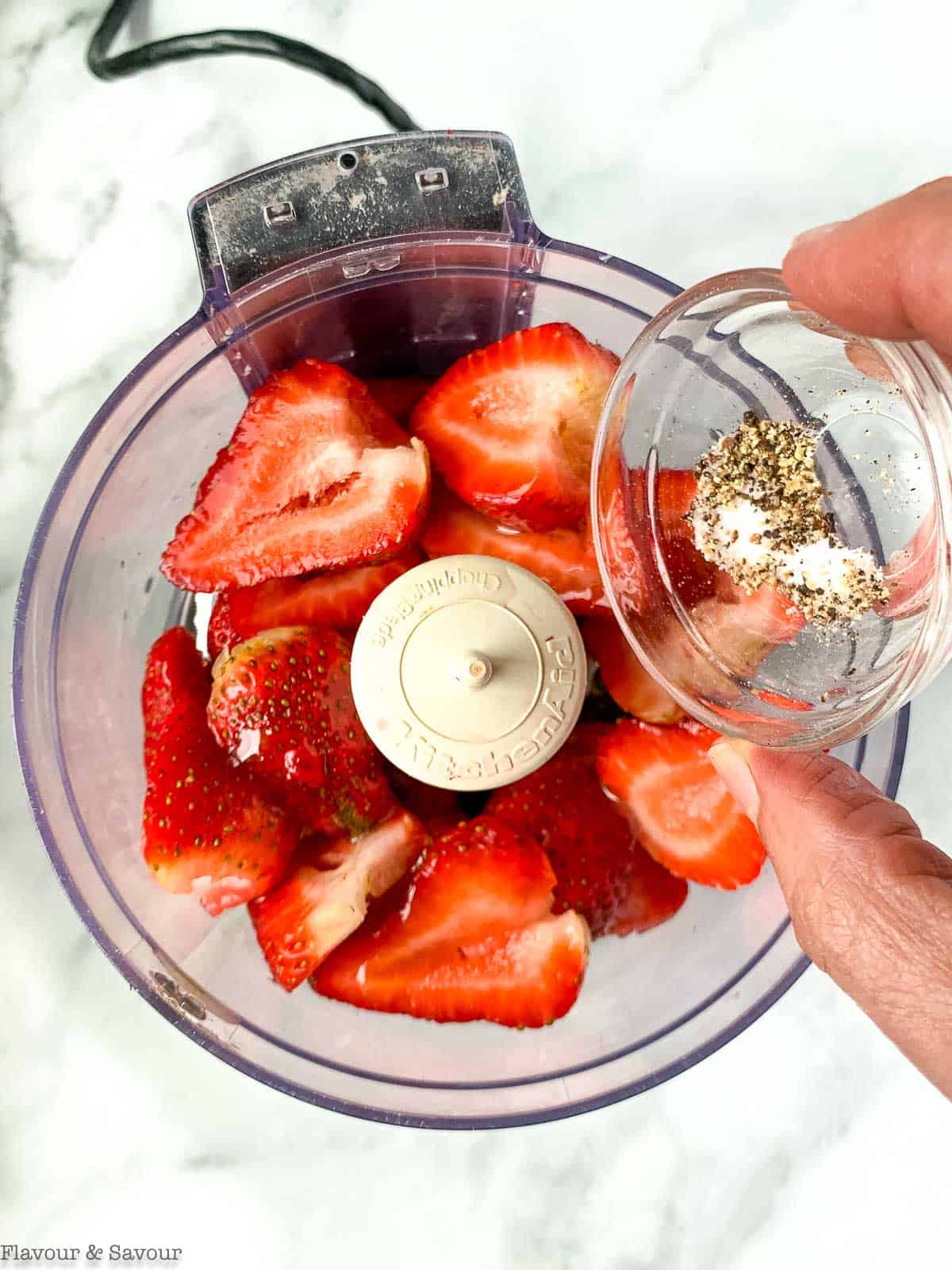 Adding salt and pepper to strawberry salad dressing ingredients.