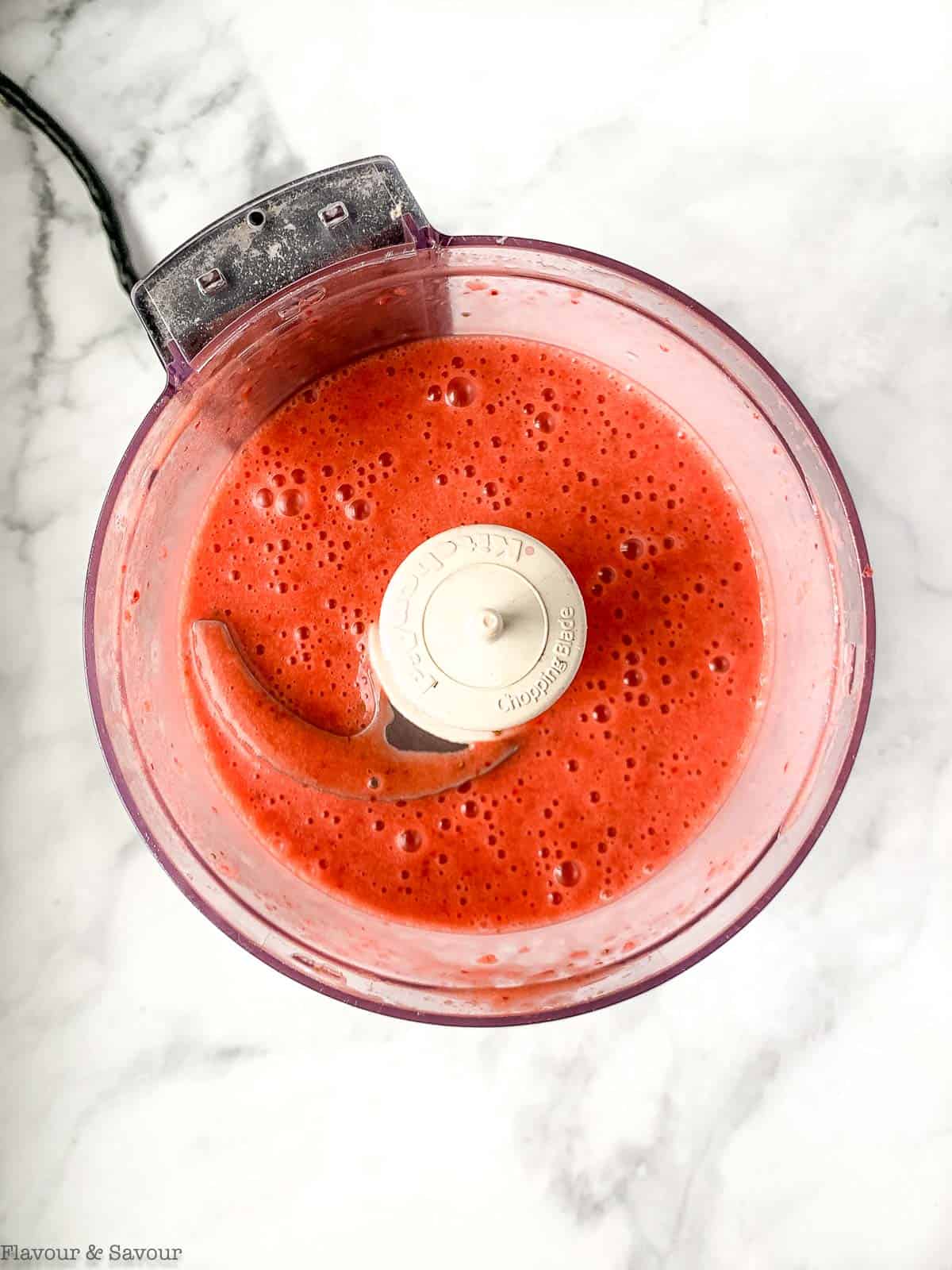 Blended strawberry vinaigrette in a food processor bowl.