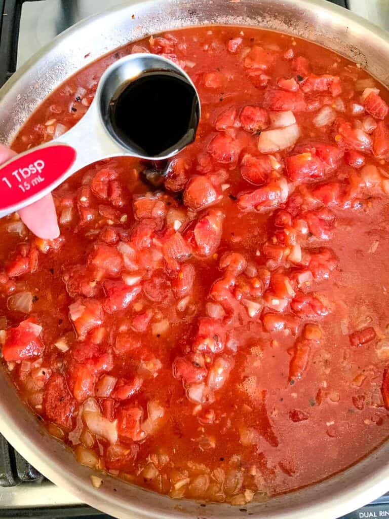 adding balsamic vinegar to tomatoes in a skillet.