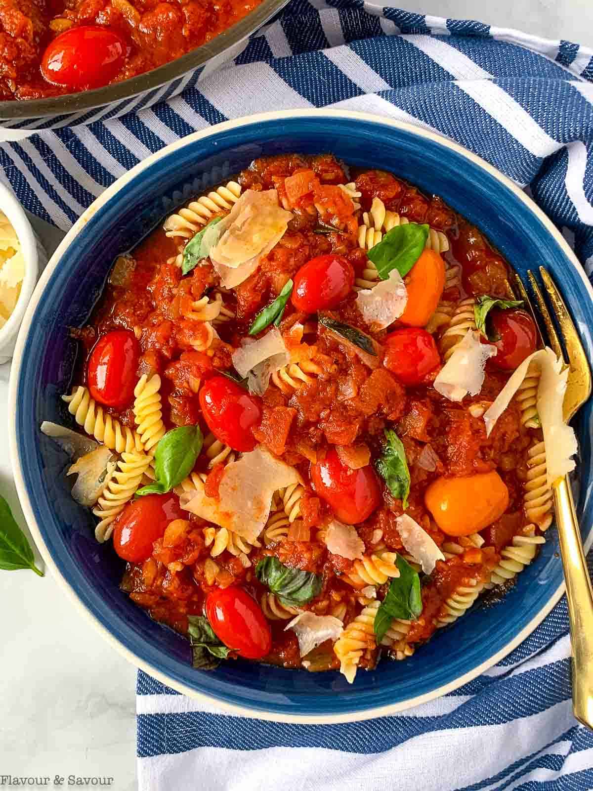 A bowl with gluten-free pasta, arrabbiata sauce and cherry tomatoes.