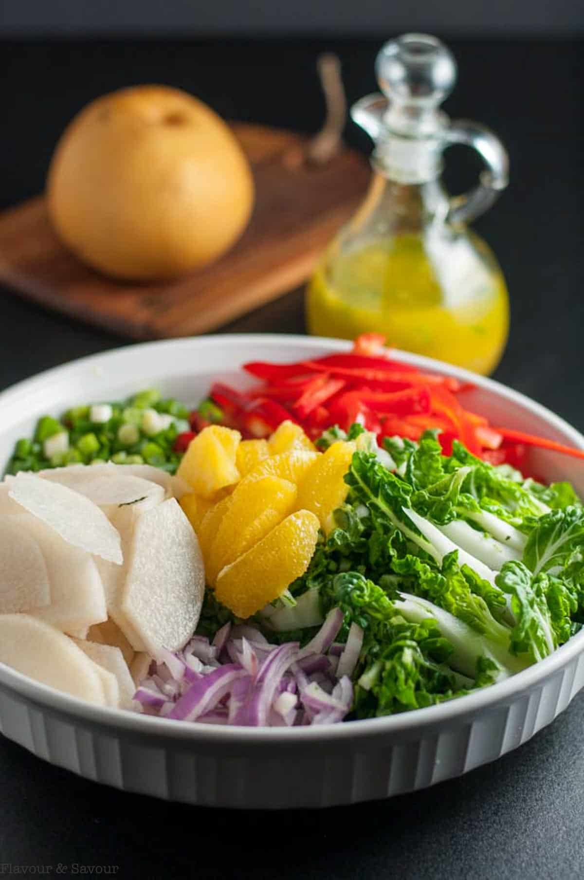 Baby bok choy salad ingredients with an Asian pear and ginger orange dressing nearby.