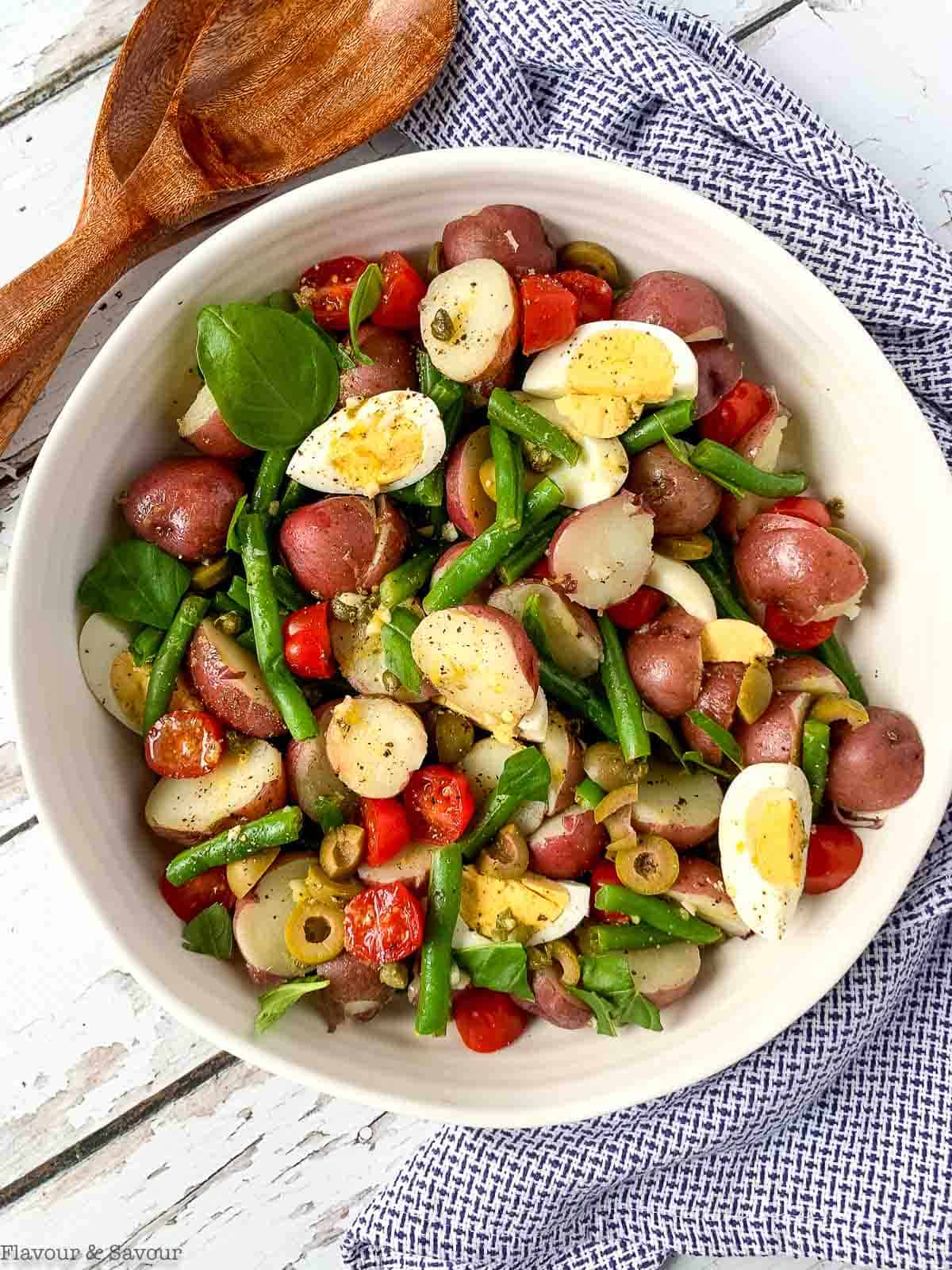 overhead view of a bowl of green bean potato salad with hard-boiled eggs and capers