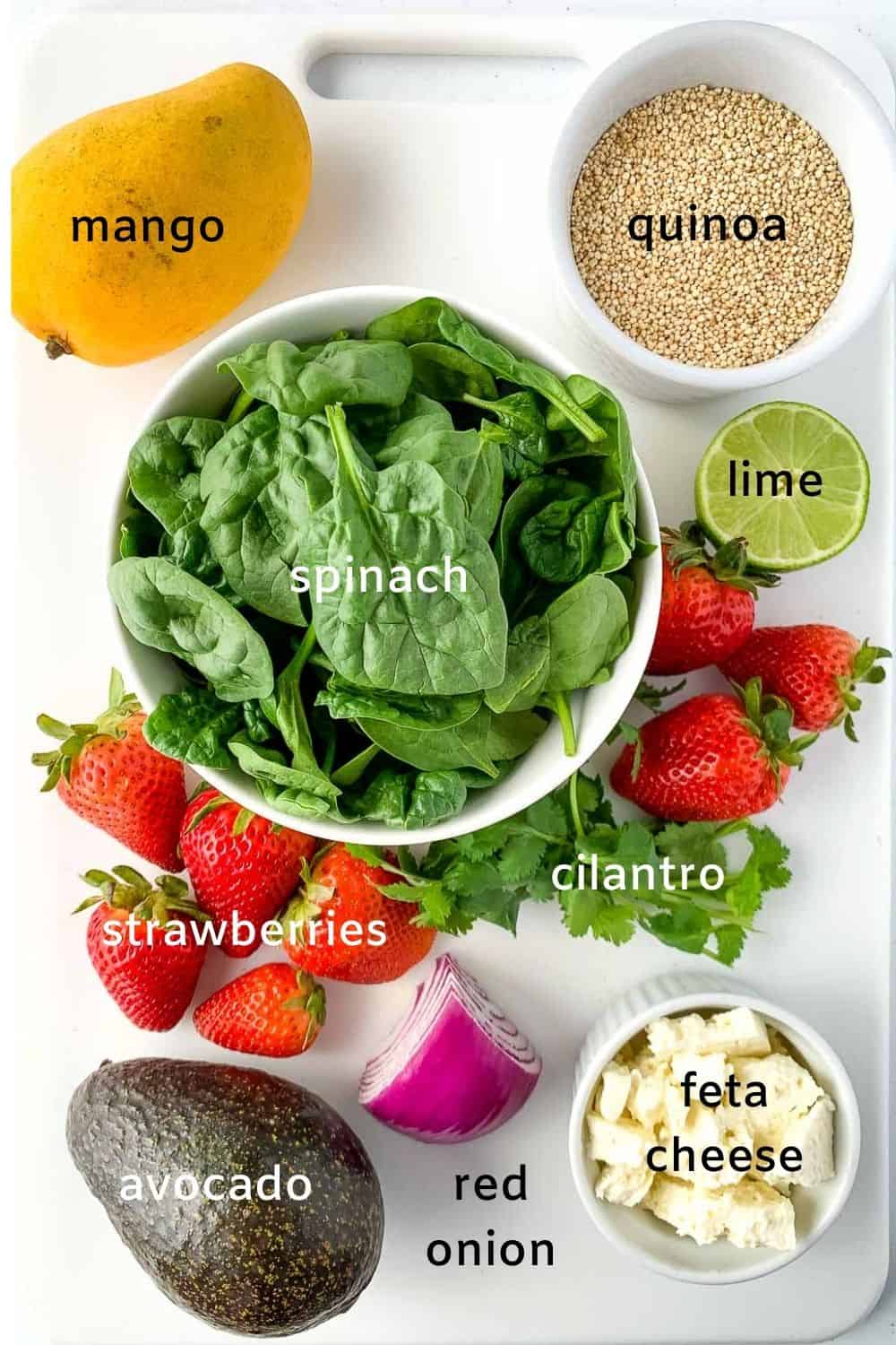Labelled ingredients for quinoa bowl with spinach, feta, strawberries and mango.