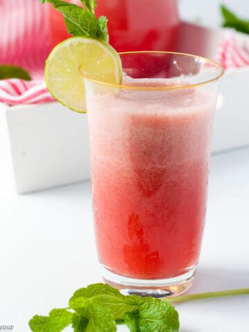 a tall glass of strawberry limeade with a sprig of mint.