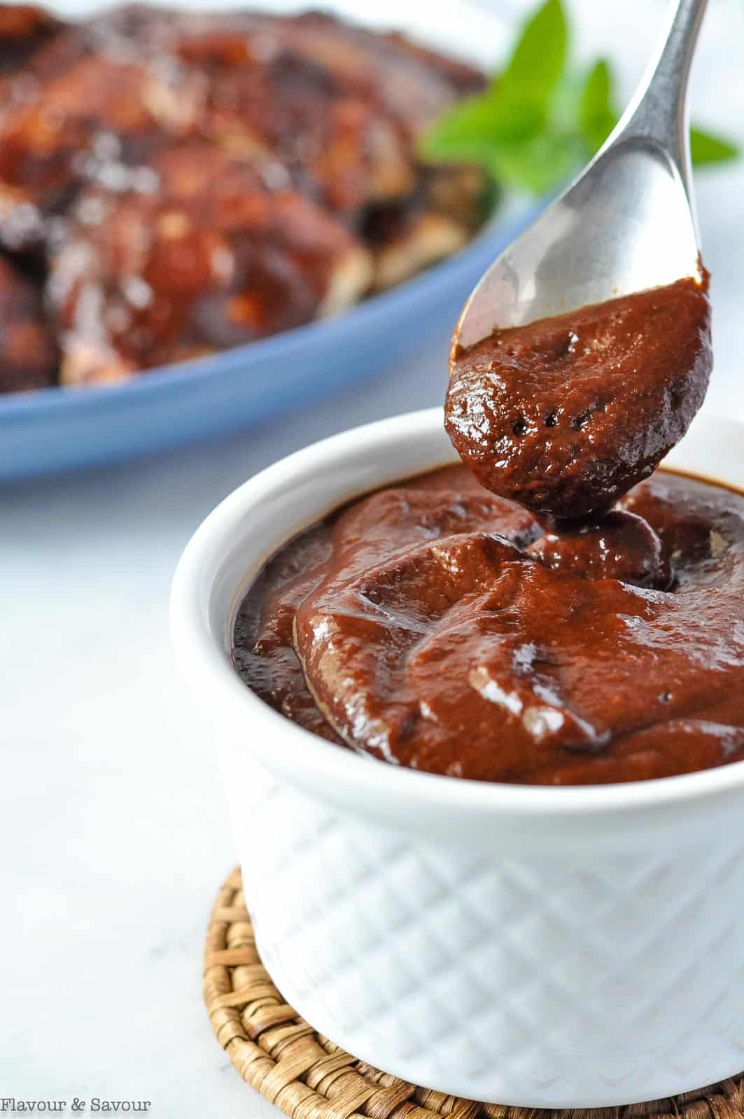 A spoonful of cherry barbecue sauce with bbq chicken.