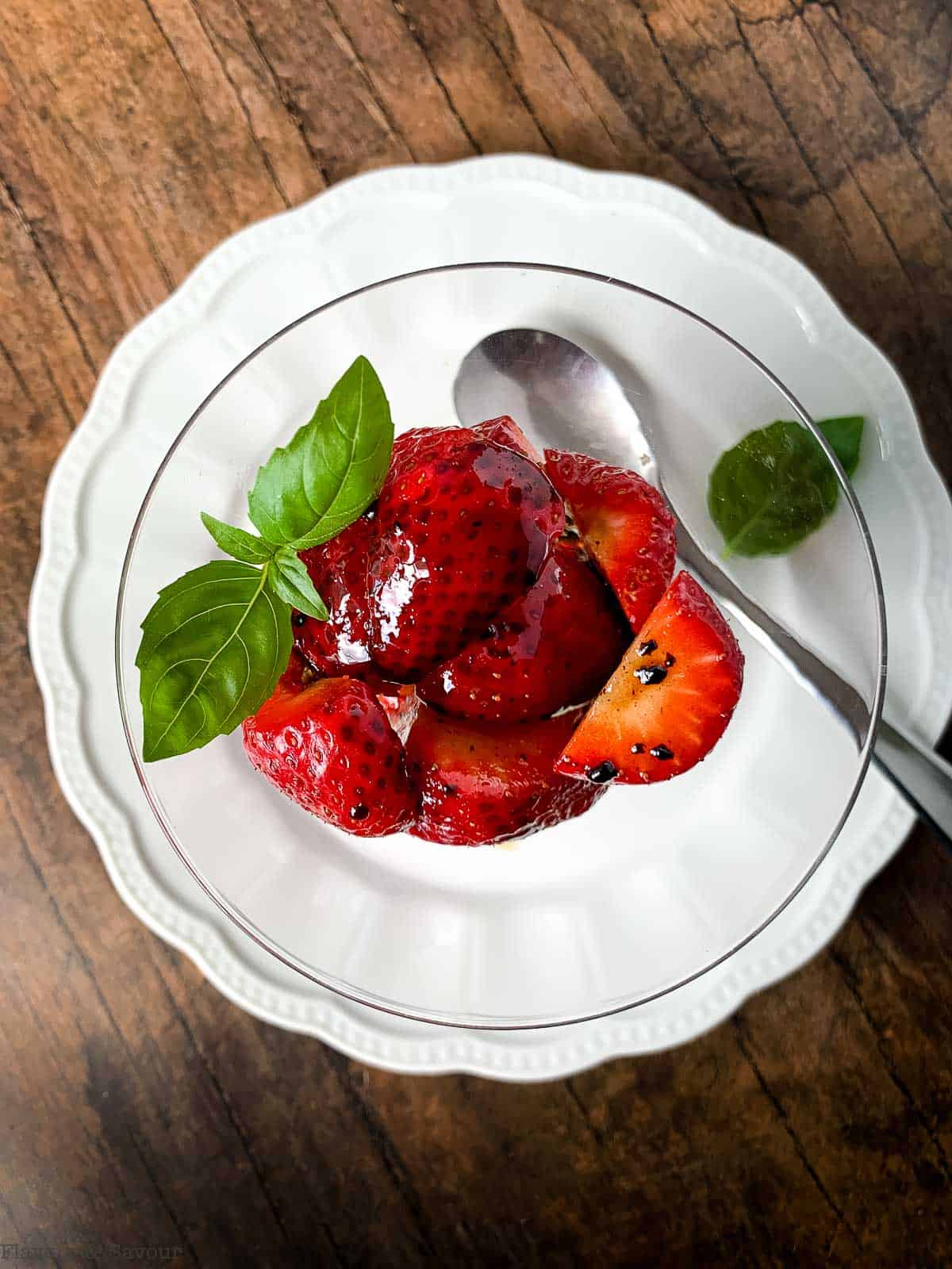 Overhead view of strawberries with balsamic glaze and basil.