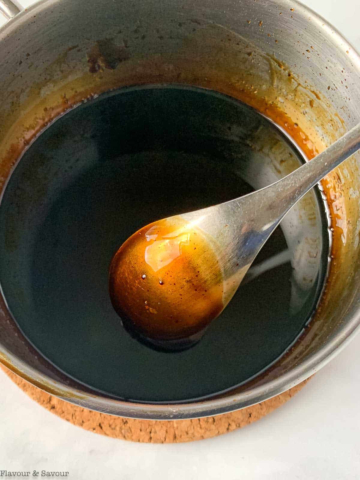 Balsamic glaze coating the back of a spoon.