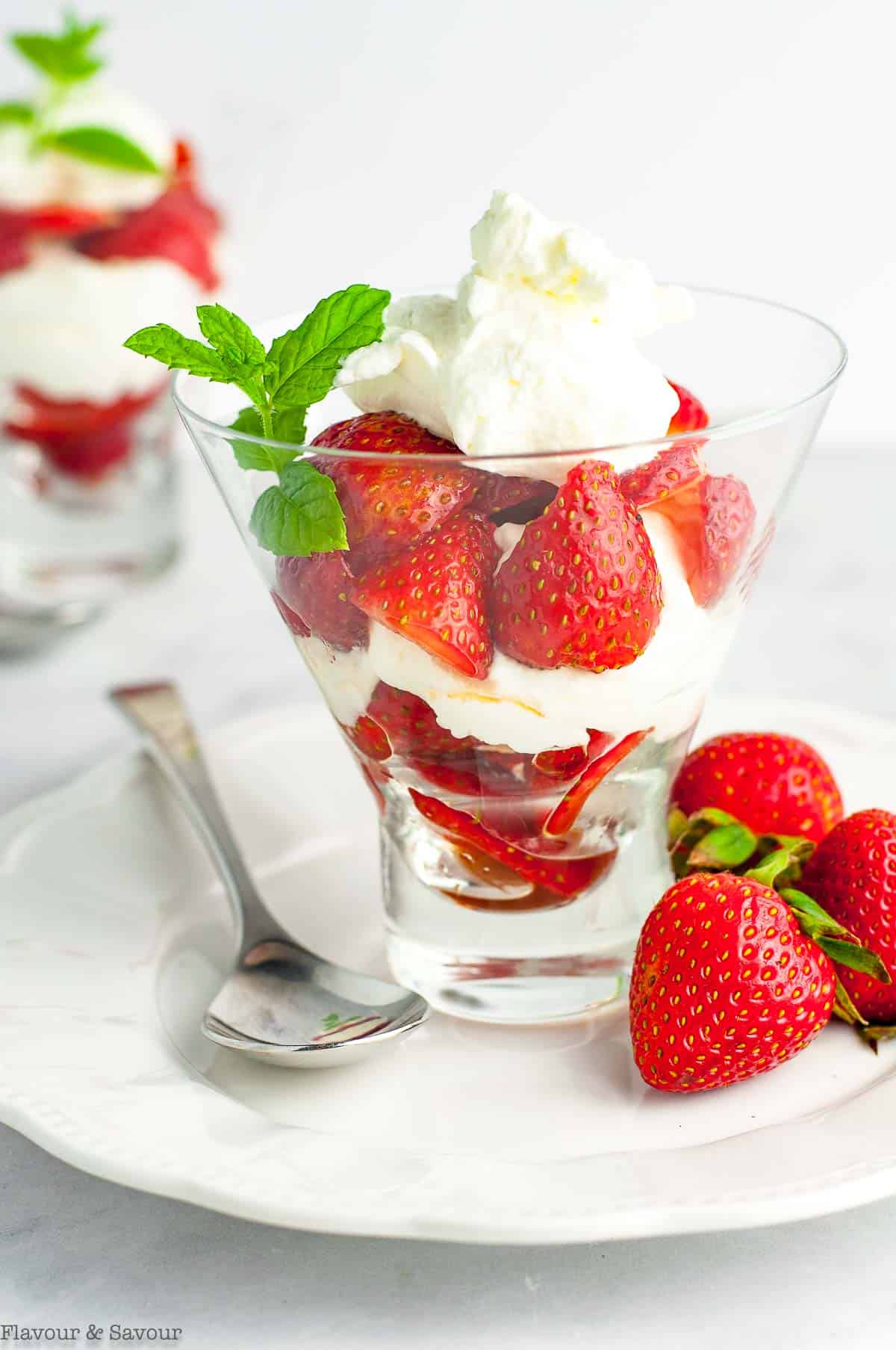 A dessert glass with balsamic strawberries and whipped cream.