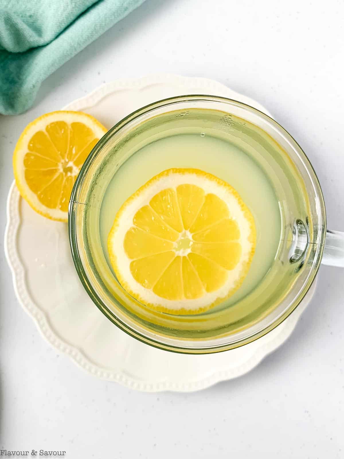 overhead view of a clear glass mug of lemon ginger tea.