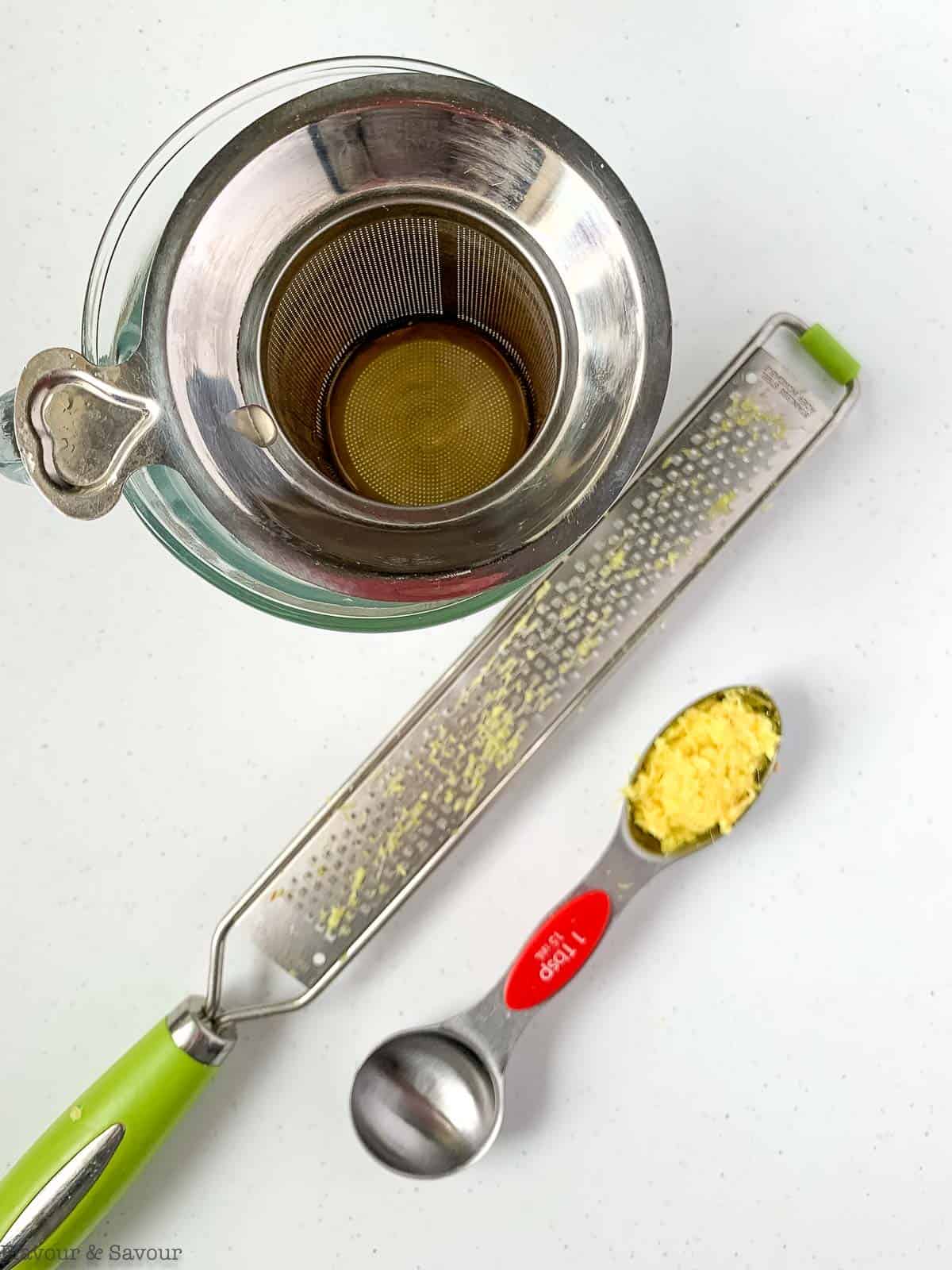 A microplane and a teaspoon with grated ginger.