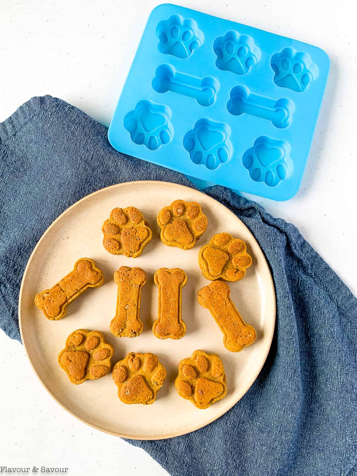 A plate with pumpkin peanut butter dog treats beside a silicone mold.