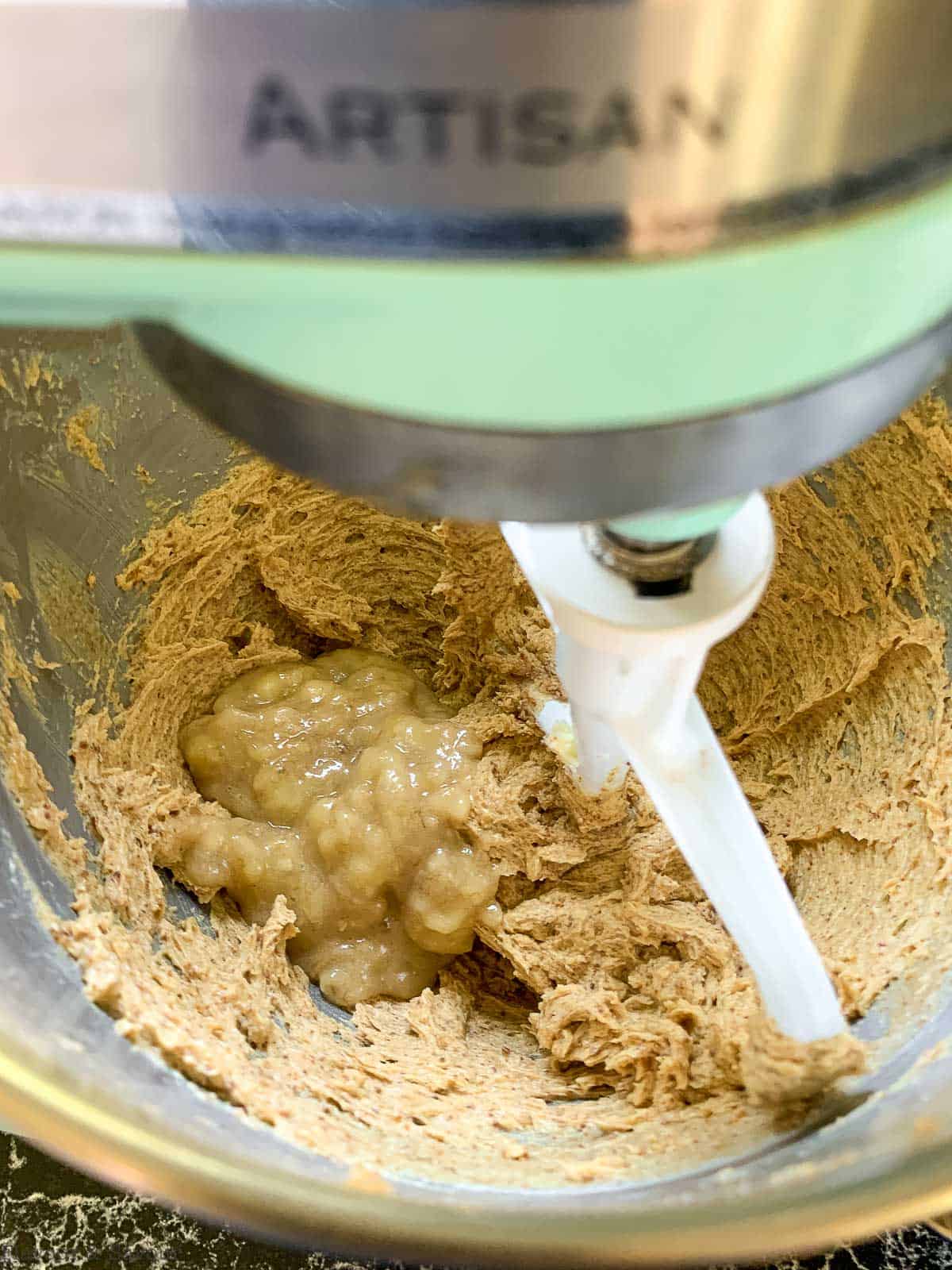 Adding mashed banana to creamed butter and sugar.