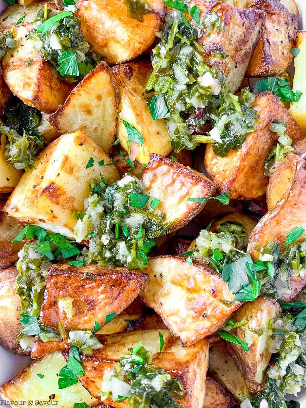 Extreme close up view of air fried potatoes with chimichurri sauce.