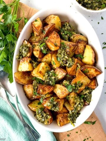 An oval bowl of crispy roasted potatoes.