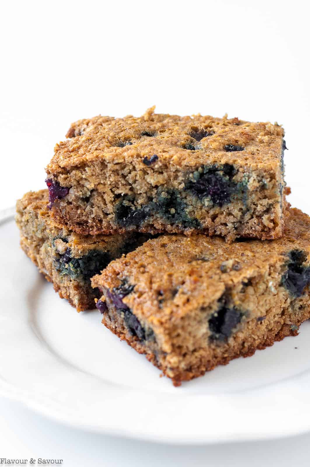Blueberry oatmeal breakfast bars stacked on a white plate.