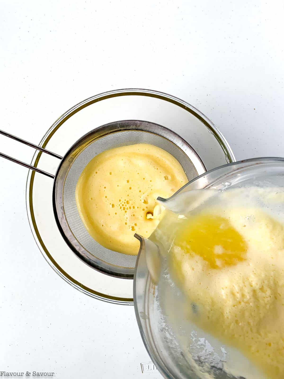 Straining pineapple agua fresca through a sieve.