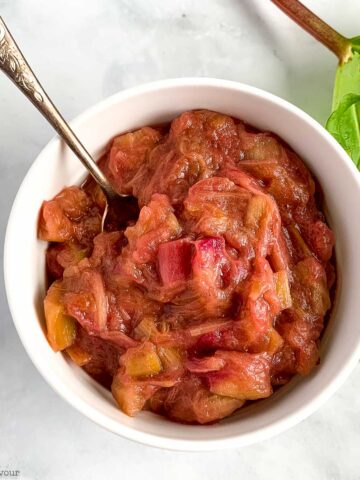 Rhubarb compote in a small bowl with a spoon.