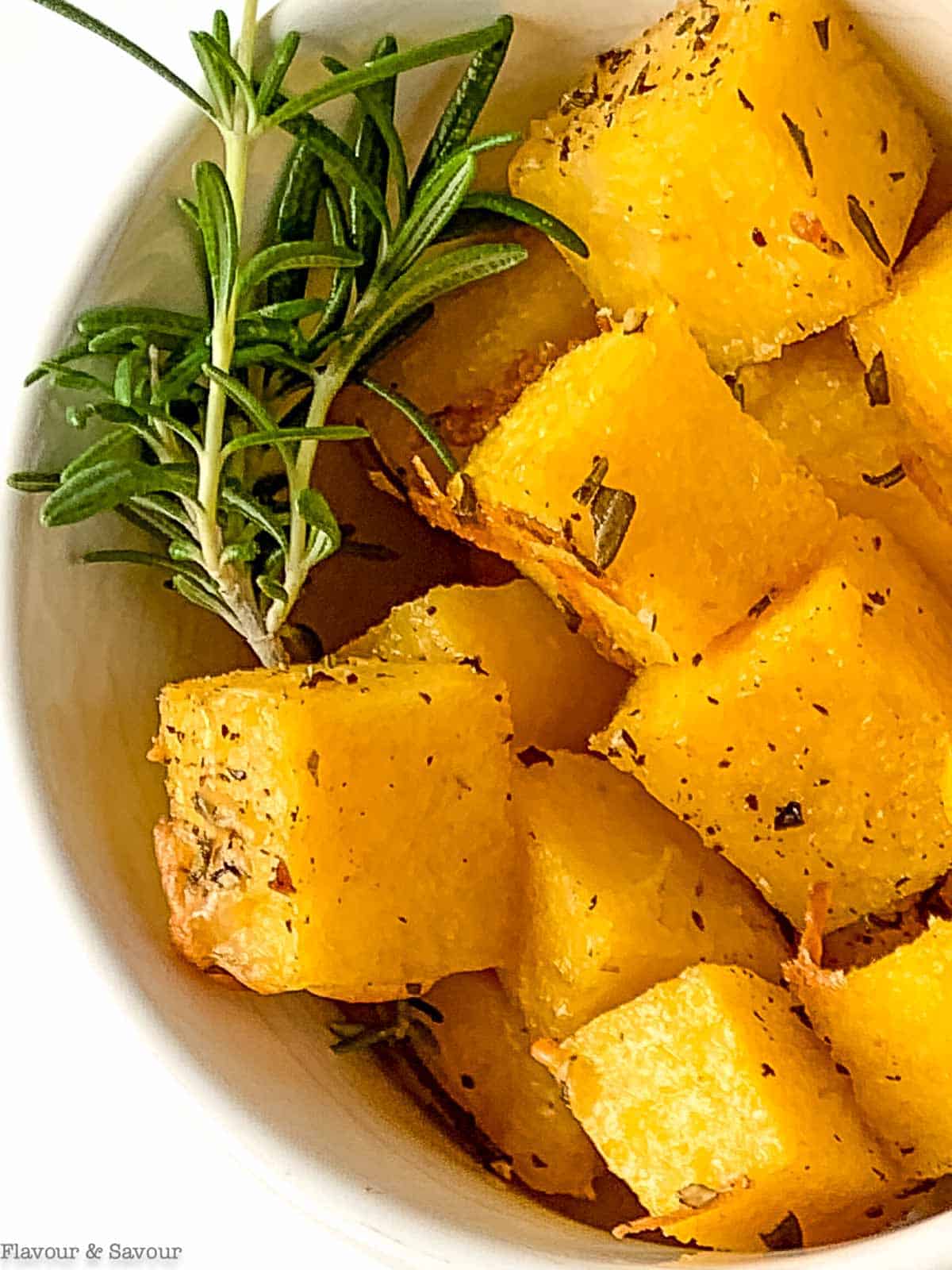 Close up view of a bowl of Italian herbed polenta croutons with rosemary.