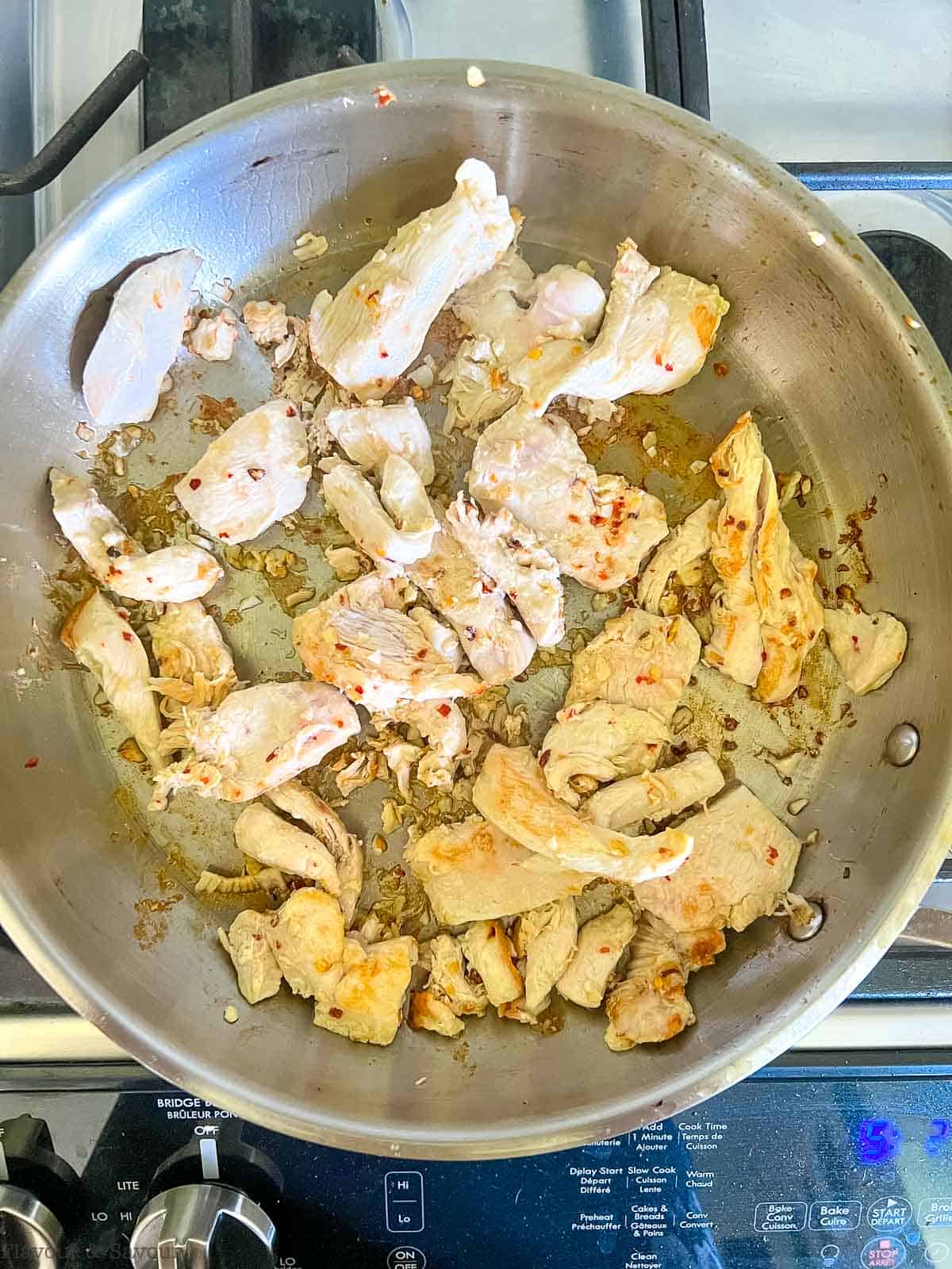 Browning chicken in a skillet for Thai red curry with chicken.