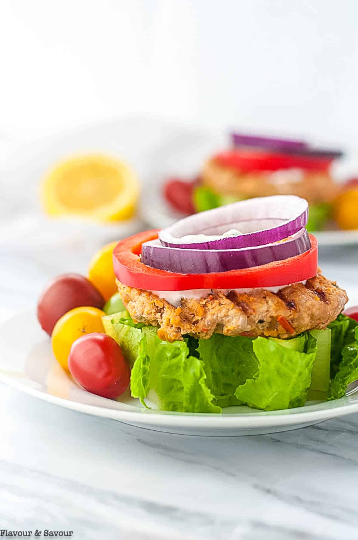 Moroccan-style open-face harissa chicken burger on a bed of lettuce.