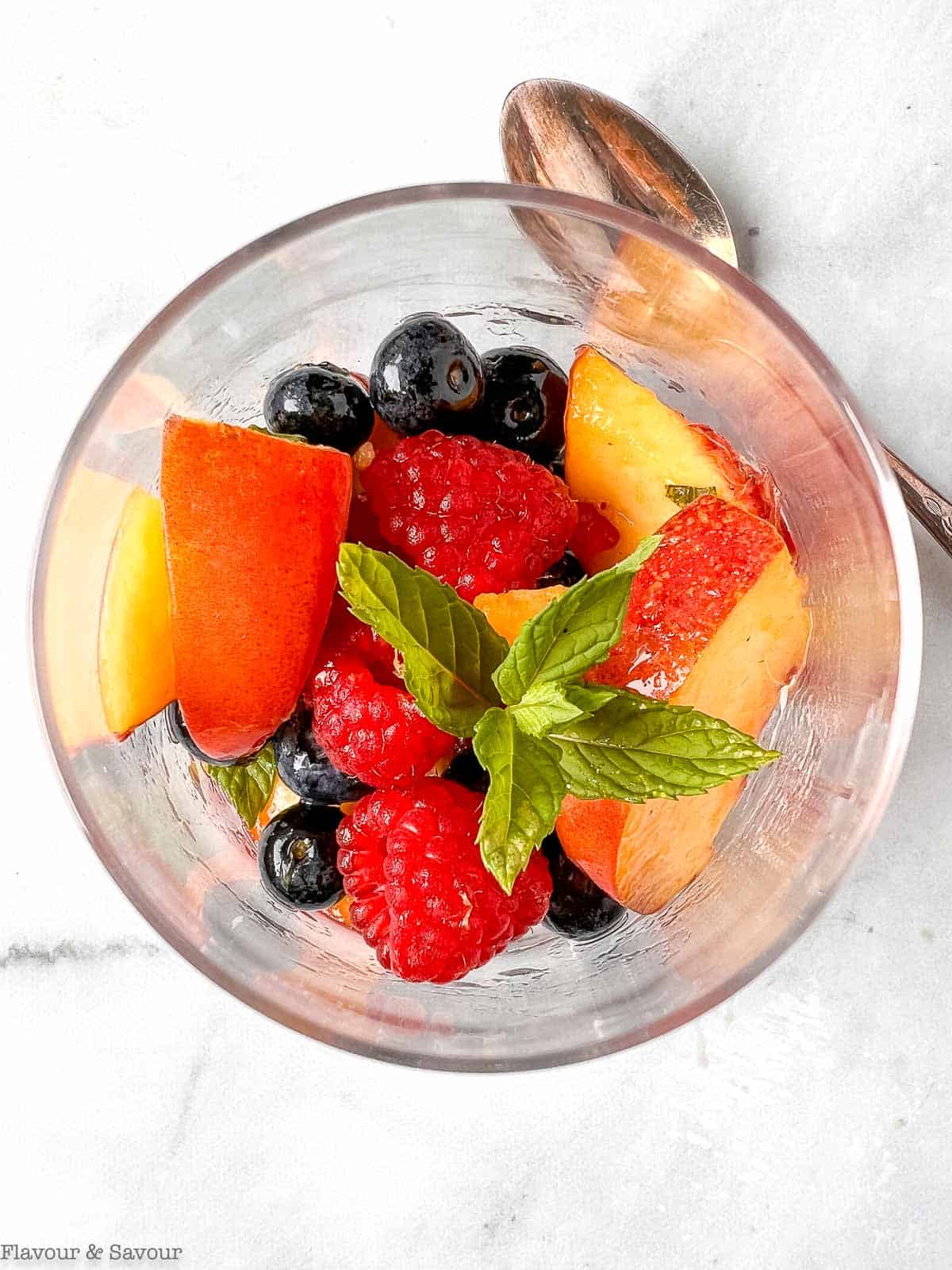 Overhead view of a dessert glass with nectarines and berres in Prosecco.