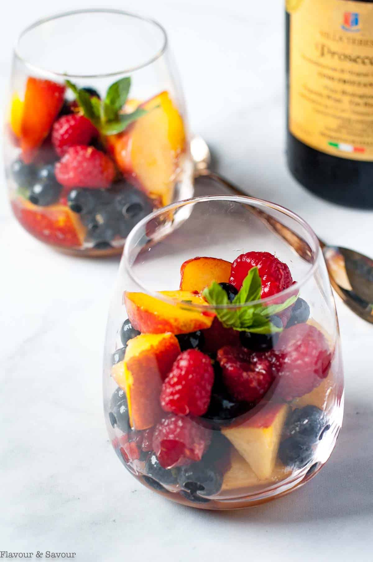 Two dessert glasses with nectarines and berries with Prosecco.