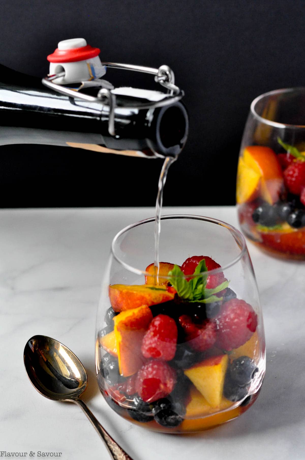 Pouring Prosecco into a glass of nectarines and berries.